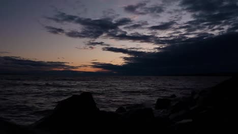 Lapso-De-Tiempo-Al-Atardecer-Con-Olas-Rompiendo-En-Las-Rocas-En-La-Costa-Y-Hermosas-Nubes-Corriendo-Por-El-Cielo-En-El-Lago-Nipissing,-Ontario,-Canadá