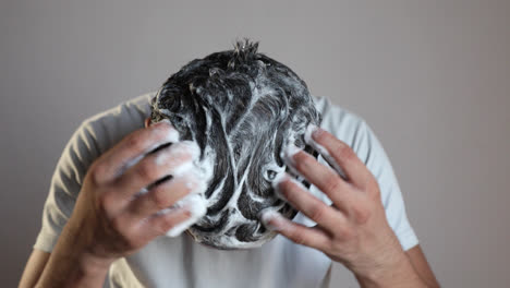 hombre limpiándose el cabello con una espuma de champú anticaspa, usando un producto para el cuidado del cabello