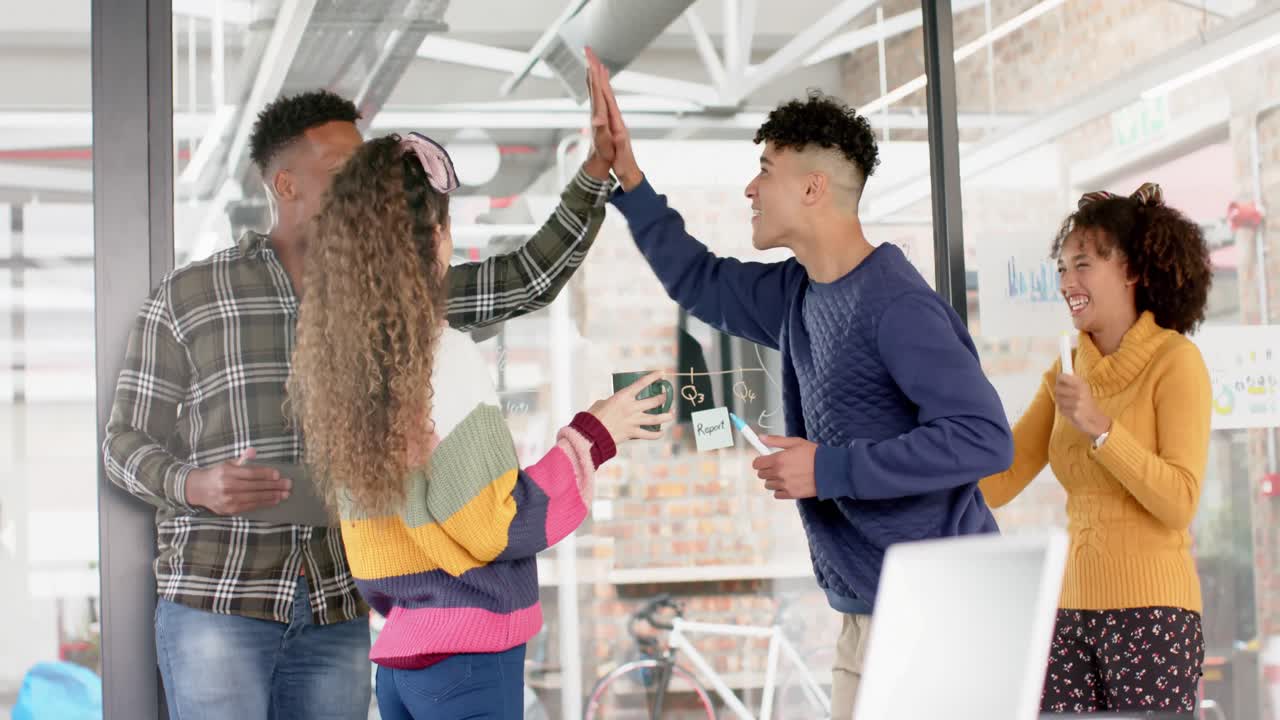 Happy diverse business people high fiving at meeting in office in slow motion