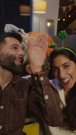 Vertical-Video-POV-Shot-Of-Friends-Dressing-Up-At-Home-Celebrating-At-St-Patrick's-Day-Party-Making-Video-Call-On-Mobile-Phone