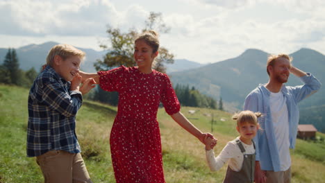 eltern lächeln, kinder laufen im grass mountain valley. die familie fühlt sich glücklich.