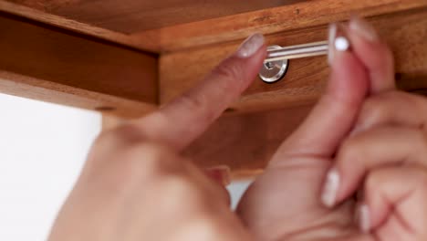 hands use a hex key to tighten screws on wooden furniture, demonstrating assembly in a well-lit environment