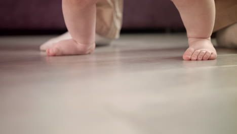 Little-feet-walking-on-floor.-Child-steps-with-father-support