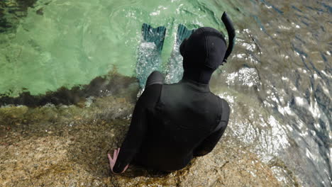 un buzo cayendo en el agua cristalina del océano en un traje de buceo