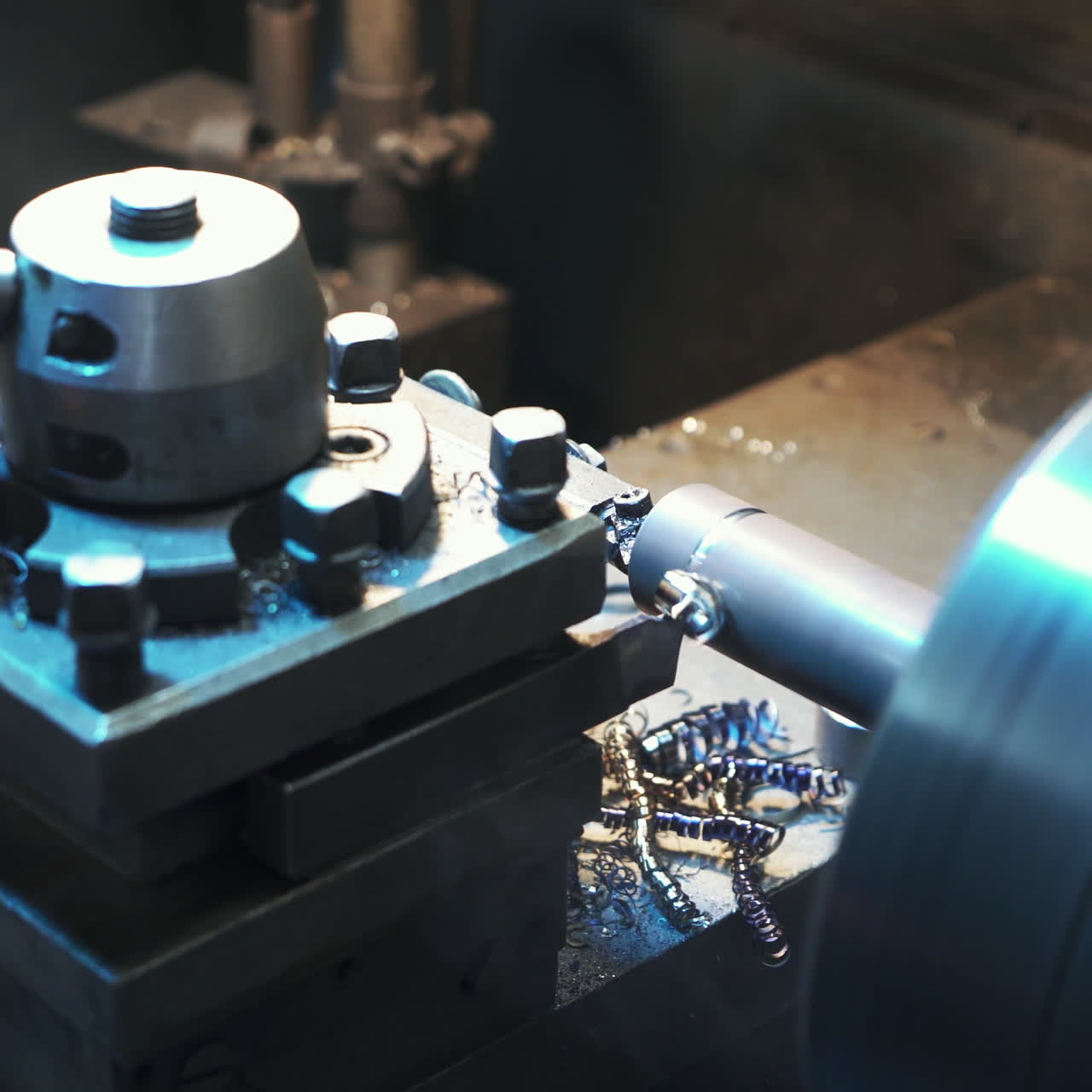 Metalworking industry: cutting steel metal shaft processing on lathe machine in workshop. Selective focus on tool