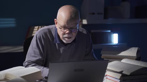 researcher, journalist, historian, mature old man reading a book alone in a dark room.