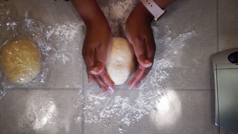 woman kneading ball of dough on home kitchen countertop, close up from above