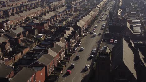 aerial rising view establishing rows of terraced houses in dentons green, st helens with a long road leading towards the bustling town centre