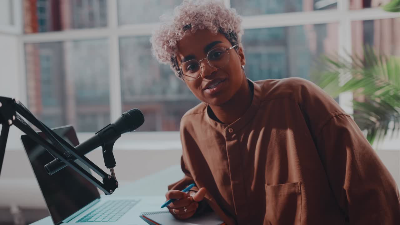 African woman sitting in front of camera recording video with podcast microphone
