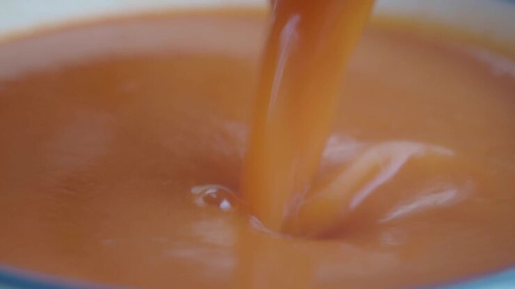 Close-up of a Spoon Stirring Creamy Orange Soup