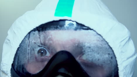 medical staff in ppe suit with goggles misting up, opens big round eyes in a sudden - extreme close up