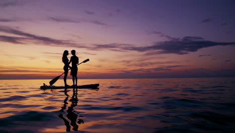 couple paddleboarding at sunset