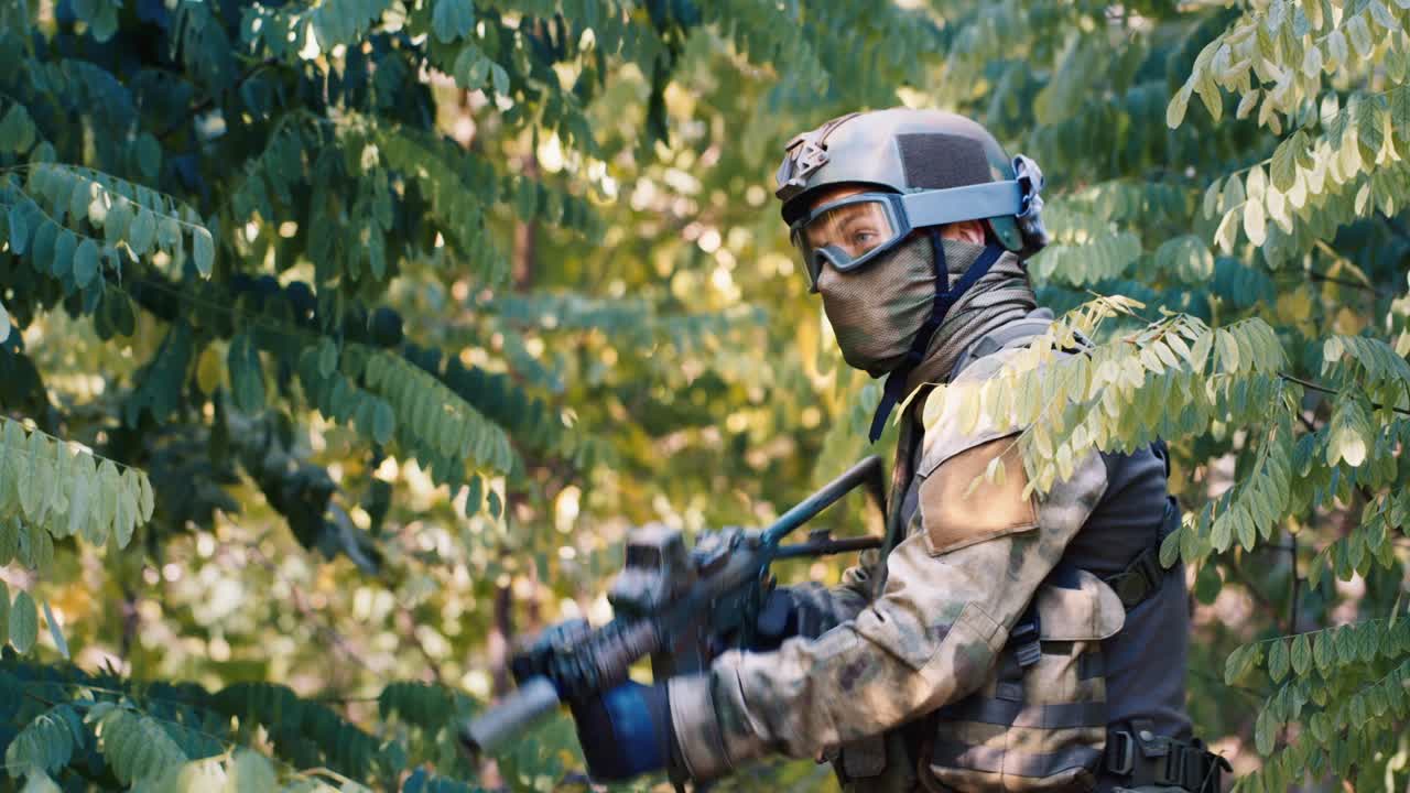 airsoft 플레이어가 나무 덤불에 숨어 있습니다.