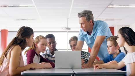 Teacher-assisting-schoolkids-on-laptop-4k