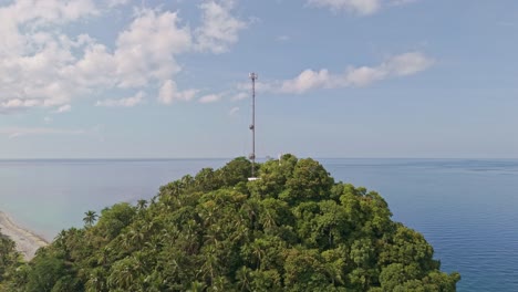 a cell tower on top of a jungle covered hill, with views over the vast coastline and mountainous landscape