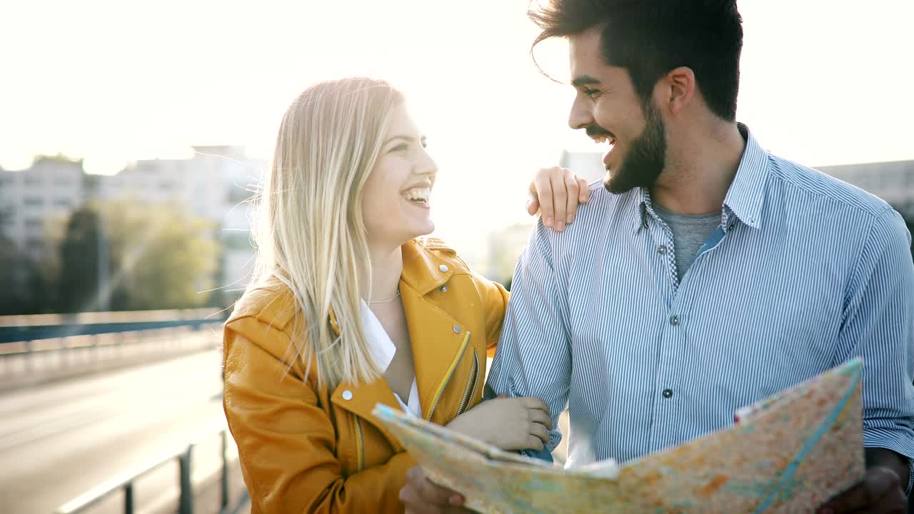 una pareja sonriente y enamorada viajando con un mapa al aire libre