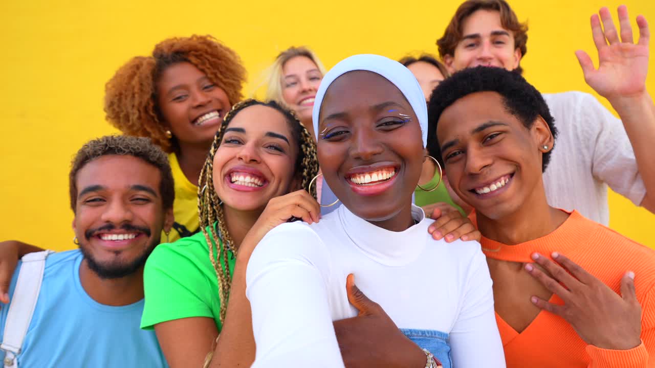 A diverse group of friends posing together against a yellow background