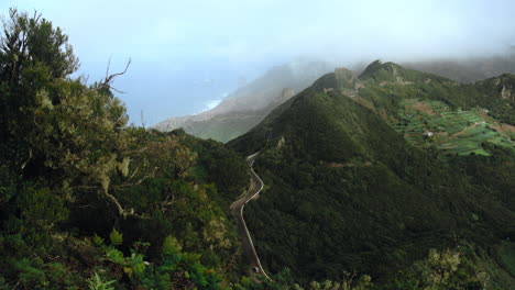 timelapse of fog flowing over a mountain range with the ocean in the background and a street with driving cars