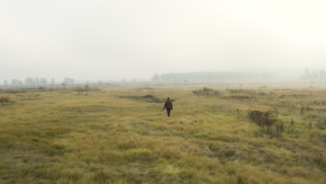 young documentarist wading through tall grass,misty moorland,czechia