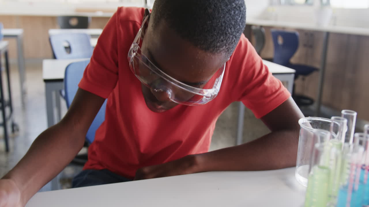 Conducting science experiment, student observing petri dish in school laboratory
