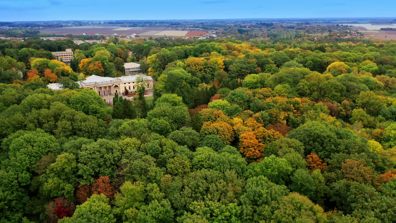 Historical palace in the beautiful green park. Cityscape and agricultural fields at backdrop. Aerial view.