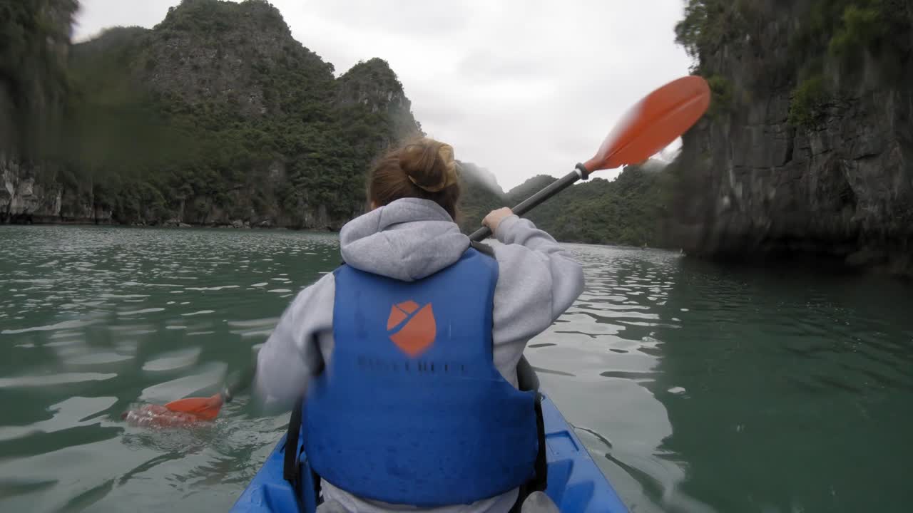 Ripresa in soggettiva di una donna in kayak che pagaia, vista da dietro