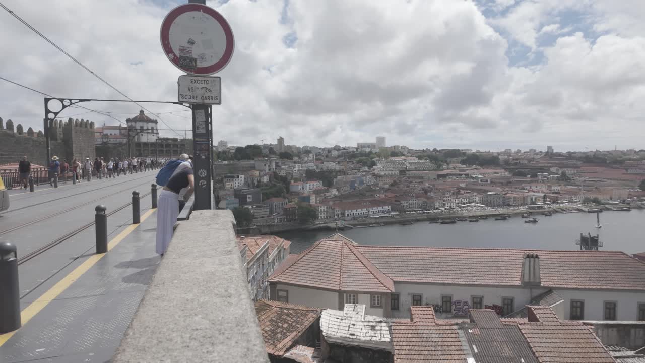 Modern yellow tram crosses the Dom Luís I Bridge in Porto on a bright cloudy day