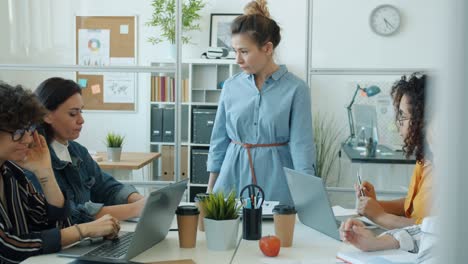 mujer asiática enojada gritando a un grupo multiétnico de empleados hablando y gestando en el trabajo
