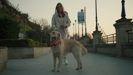 portrait of a young girl and her light-colored dog posing against the backdrop of the embankment at dawn