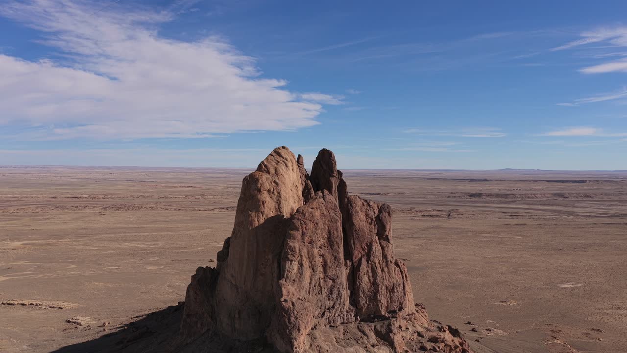 Una órbita circular de dron se centra en un monolito de puesto de avanzada de ciencia ficción remoto en un paisaje desolado de un planeta árido, mostrando la formación rocosa estéril y la vasta inmensidad de un entorno futurista