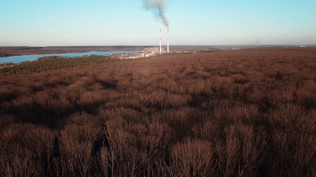 removed view of the autumn forest and power station near the river. Aerial view