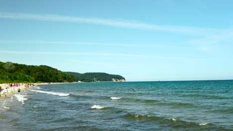 A-view-of-the-GdaÅ„sk-bay,-a-cliff-in-Gdynia-can-be-seen-in-the-distance,-the-sea-is-calmly-waving-and-has-a-dark-colour