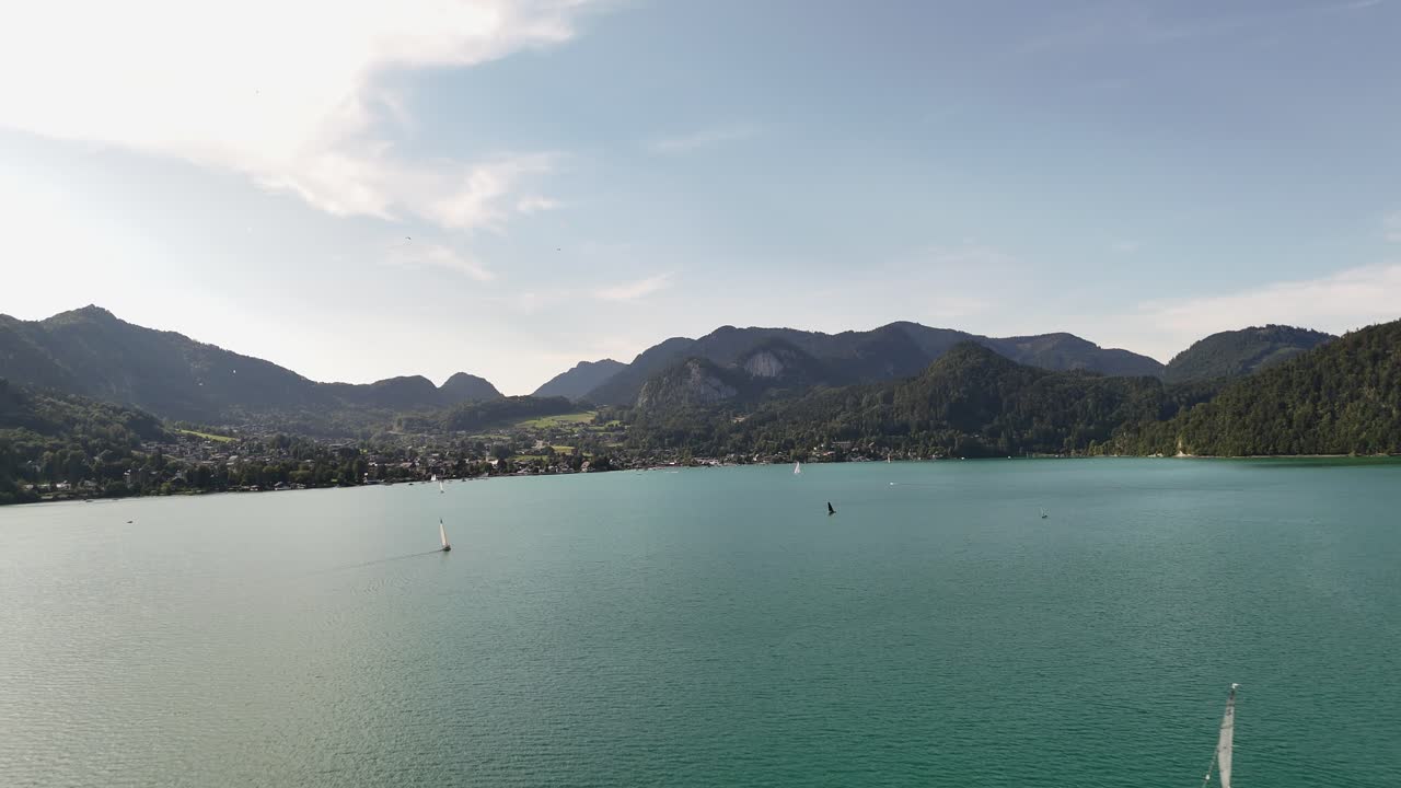 잔잔한 산과 작은 마을을 배경으로 한 몬드시의 푸른 물 위의 항해 보트