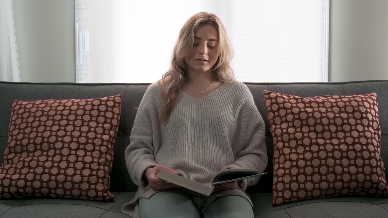 Young woman opening a book in her living room