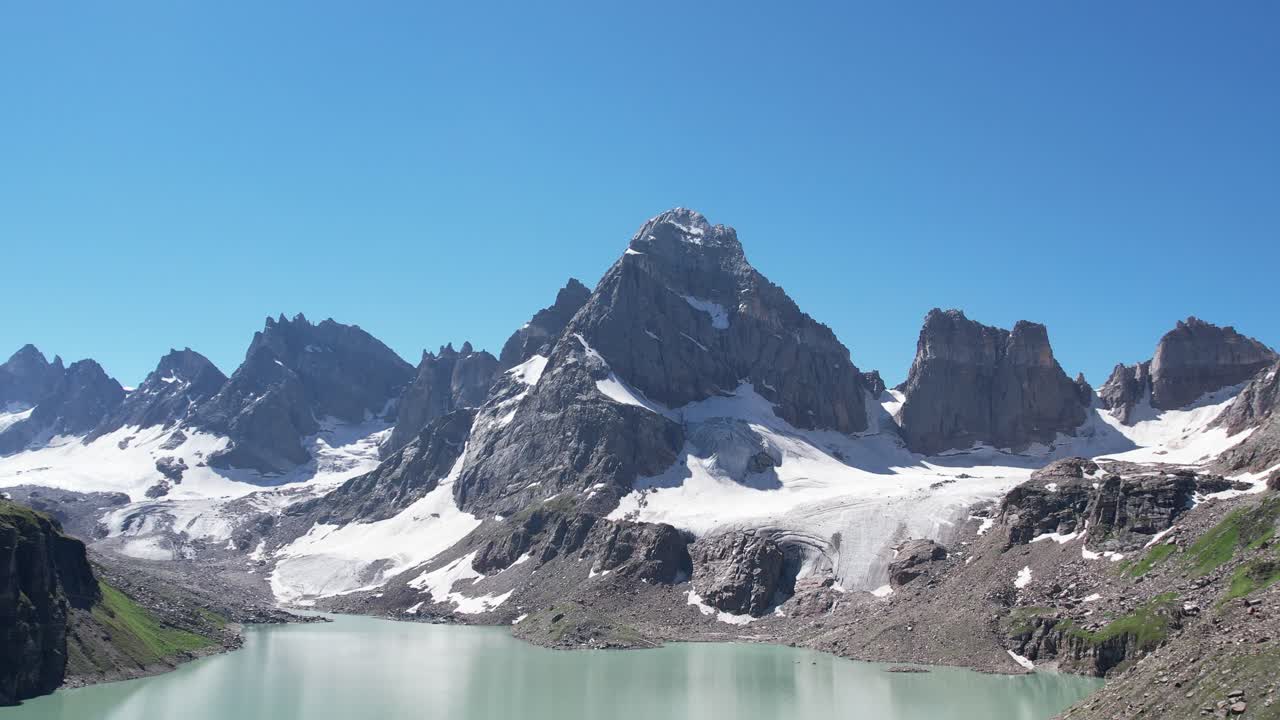 acantilados cresta montañosa con un lago en primer plano - rocas ígneas y metamórficas - nieve con acantilado montañoso en el fondo - región del himalaya inferior