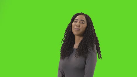 portrait of woman against green screen smiling and laughing at camera