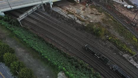 Toma-Aérea-De-Arriba-Hacia-Abajo-De-Un-Ferrocarril-Industrial-Lentamente-Sobre-Vías-En-El-área-Suburbana-De-La-Ciudad-De-Atlanta