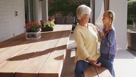 Happy-grandmother-seating-on-bench-and-hugging-little-girl-4K-4k