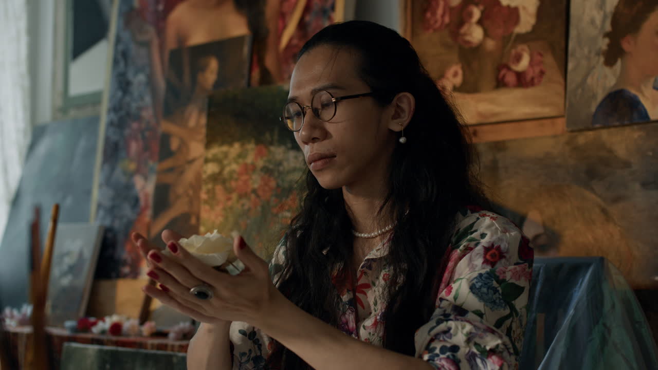 Artist focuses on painting in a colorful studio, deep in creative thought