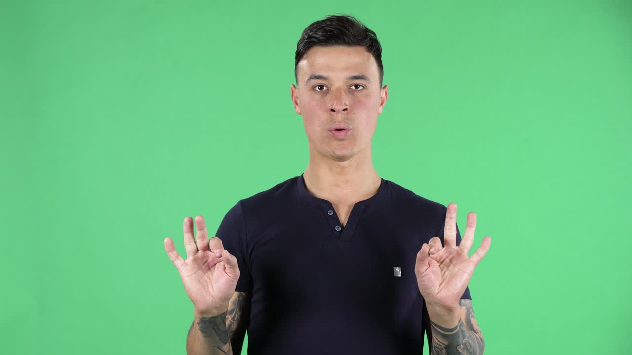 잘생긴 젊은 남자의 초상화가 카메라를 보고 휴식을 취하고 명상하고 있습니다. 녹색 화면