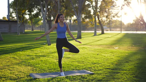 Eine-Schöne-Junge-Yogi-Frau-Lacht,-Während-Sie-In-Einer-Einbeinigen-Gebetshände-Yoga-Pose-Im-Park-Bei-Sonnenaufgang-Umfällt-Und-Das-Gleichgewicht-Verliert