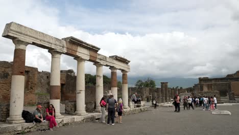 A-slow-motion-establishing-shot-of-the-entrance-of-the-building-of-Eumachia-panning-across-the-courtyard-to-reveal-the-famous-statue-Centauro-di-Igor-Mitoraj,-Pompeii,-Italy