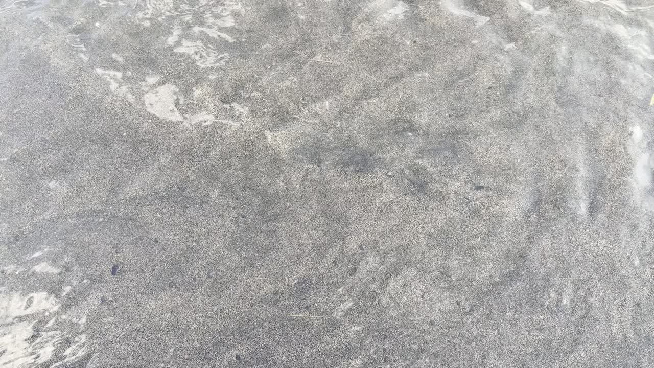 Clear Water Flowing Over Light Sand on a Beach