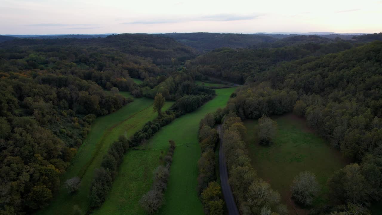Aerial view of lush green valley near Bonaguil Castle, France at dusk