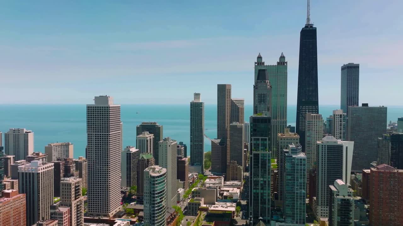 Vista aérea do skyline do centro de Chicago com 875 North Michigan Avenue elevando-se acima dos arranha-céus e o Lago Michigan cintilando ao fundo em um dia claro.