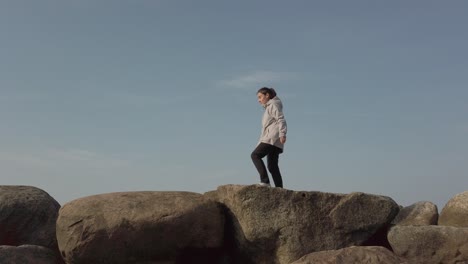 Mujer-Caminando-Y-Saltando-Sobre-Una-Serie-De-Piedras-Grandes,-Tiro-Ancho