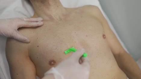 a beautician with a razor cuts the hair on a man's chest