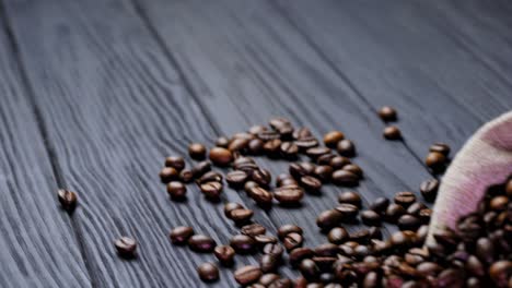 scattered coffee beans on wooden background. small sack on the table with roasted coffee beans lying nearby. brown grains of coffee.