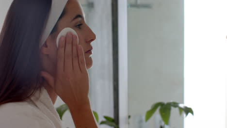 applying facial cleanser, woman in bathrobe enjoying skincare routine at home