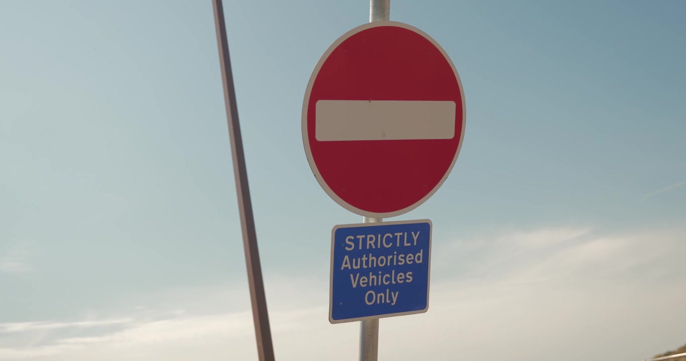 Slow motion shot of a no entry sign with authorised vehicles only text against the sky